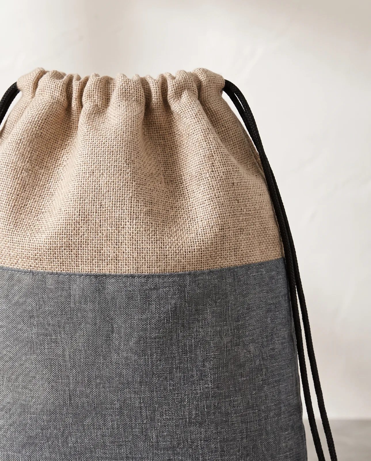 Custom cinch backpacks in Natural Beige, close view of the jute-look top panel meeting the heathered grey body with a black cord