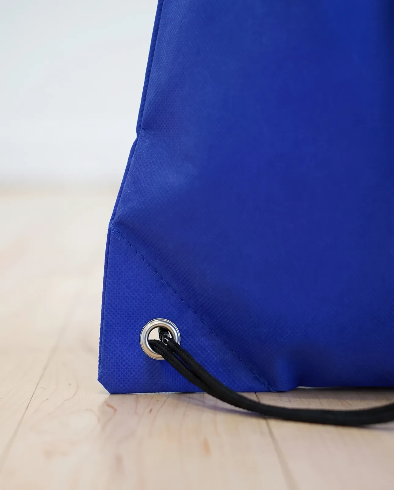 Custom drawstring bags in Royal Blue, close view of the metal grommet and black cord at the bottom corner