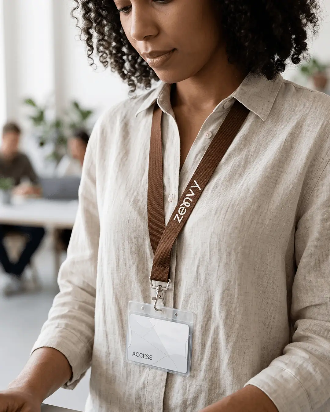 custom lanyards printed edge to edge with a sample full color design, brown strap, worn by a woman with a clear id badge holder, lifestyle view
