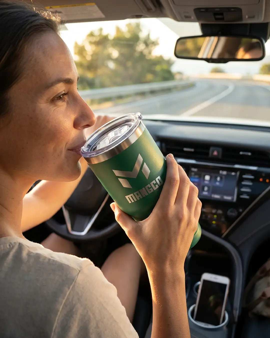 Custom insulated tumbler in Green held in hand, showing the powder finish and engraved logo