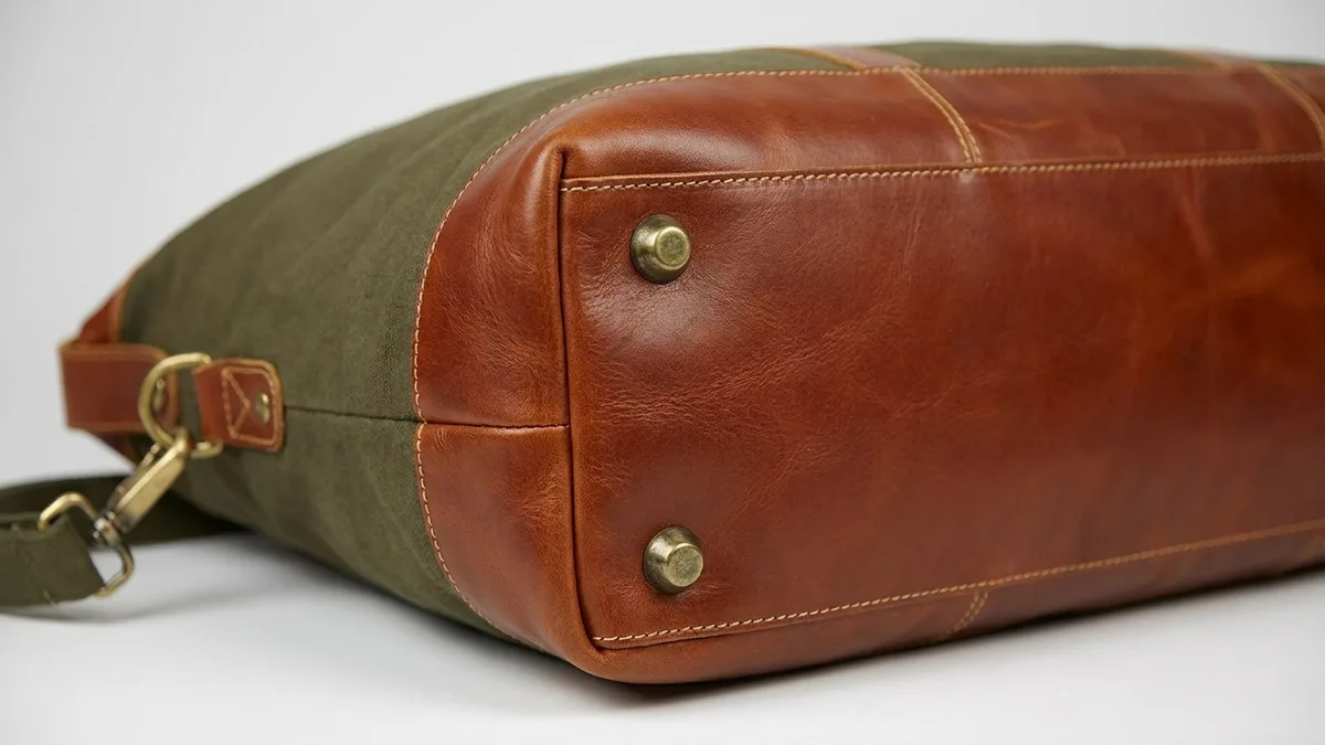 Full leather bottom with antique brass protective feet on a custom leather duffel bag — Brandevois