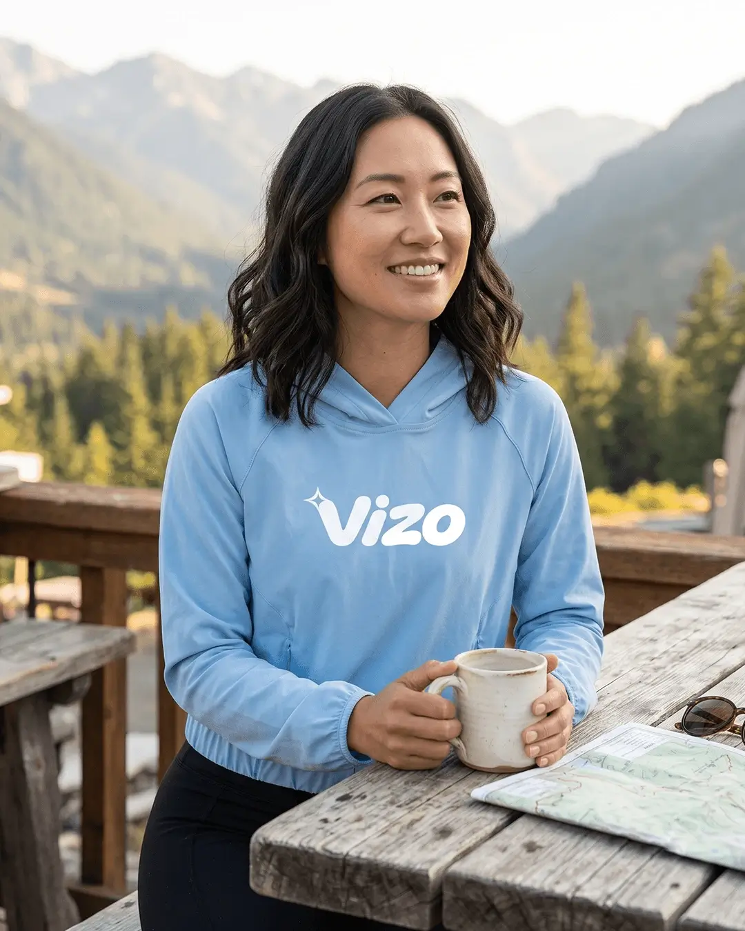 Custom sun shirts, Columbia Blue hooded pullover with a chest logo worn at a mountain lodge table