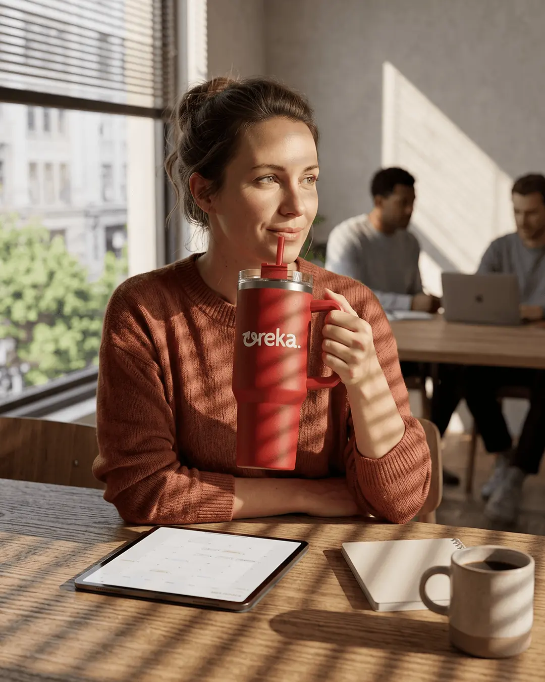Custom stainless steel travel mugs in use at a cafe table with the logo on the front