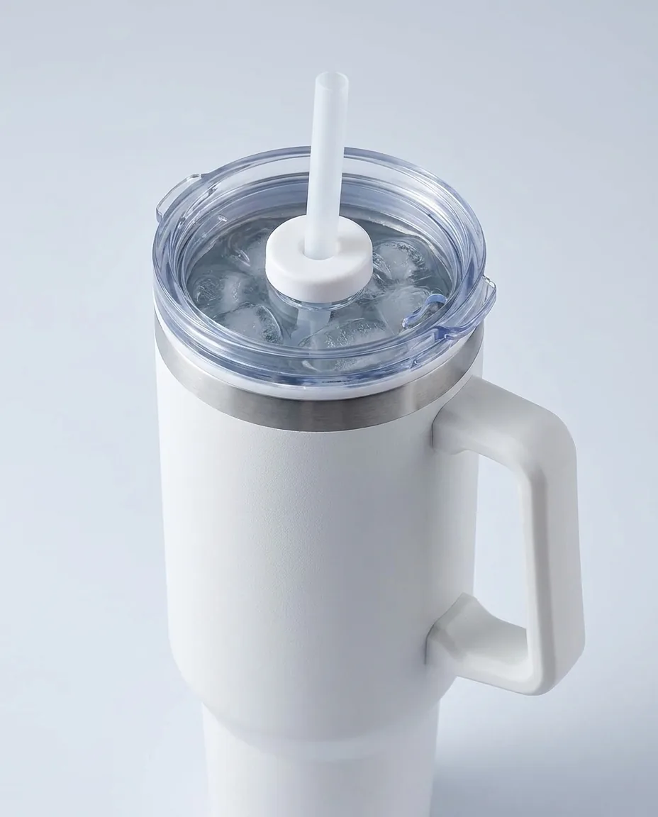 Promotional 40 oz tumbler in white matte finish shot close from above, ice water visible through the clear straw lid, with the matched straw and fixed handle in focus