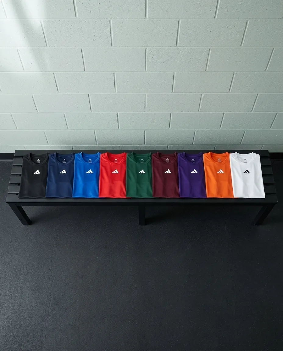 Custom Adidas shirts in nine team colors, men's Pregame tees folded in a row on a locker bench