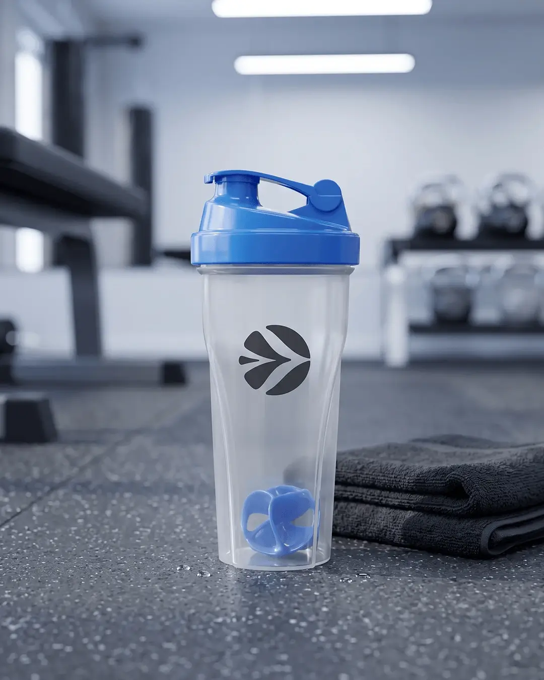 Custom shaker bottle with a blue lid and a printed logo on a gym floor beside a towel