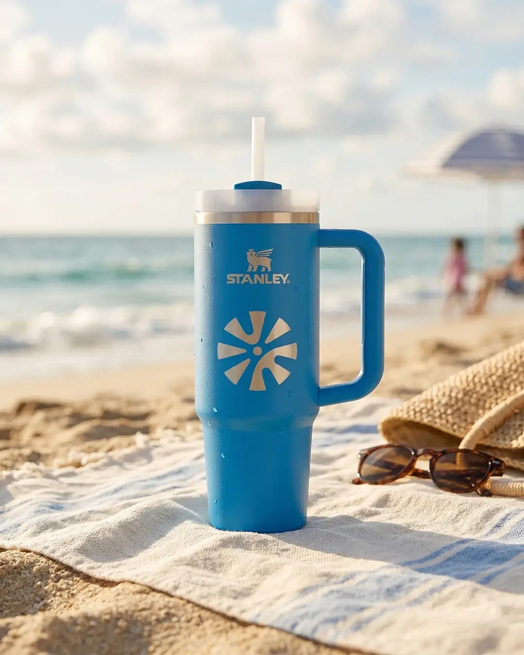 Azure blue custom Stanley Quencher with an engraved logo on a beach towel