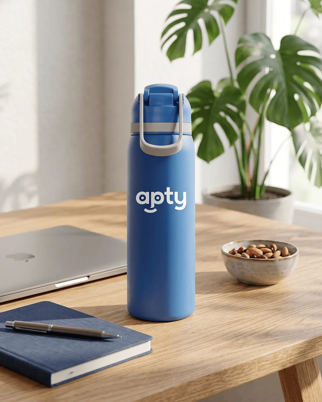Custom water bottles with straw on a desk beside a laptop with the carry handle up